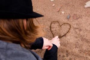 jeune homme dessinant un coeur sur le sol photo