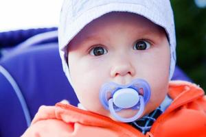 jeune bébé garçon avec un mannequin dans sa bouche à l'extérieur photo