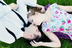 Heureux couple amoureux s'embrasser en position couchée sur l'herbe d'été photo
