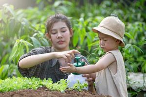 mère enseigne aux enfants à arroser les semis, la protection de l'environnement pour la nouvelle génération. photo