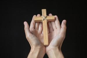 des mains humaines tenant une croix sainte et priaient pour les bénédictions de dieu, concept de dieu de culte d'amour. - image