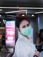 les femmes asiatiques portant des masques font du shopping au centre commercial il y a des magasins avec des étiquettes de réduction, les étiquettes sont floues, mais nous savons que c'est 70% de réduction, donc il y a une icône de panier sur la tête. photo