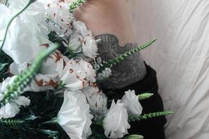 fleurs blanches, bouquet sur une feuille blanche, tatouage de jambe noire photo