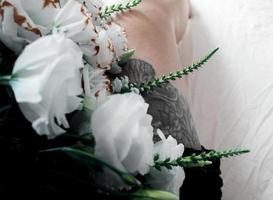 fleurs blanches, bouquet sur une feuille blanche, tatouage de jambe noire photo