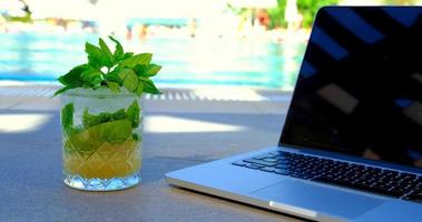 une photo d'un ordinateur portable et d'un cocktail au bord de la piscine