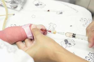image d'une infirmière mains utilise une seringue vacciner progressivement sur la main du nouveau-né malade. photo