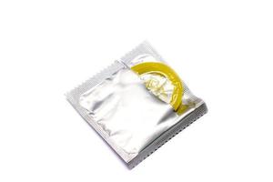 le préservatif dans l'emballage est ouvert sur fond blanc. photo
