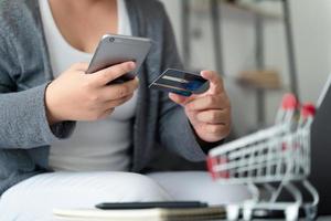 femme tenant une carte de crédit et utilisant un smartphone pour les achats en ligne, les services bancaires par Internet, le commerce électronique, dépenser de l'argent. photo