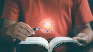 jeune homme tenant une loupe sur un livre, photo