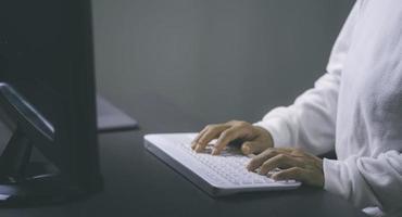 une jeune femme travaillant devant un ordinateur allongé sur le bureau , photo