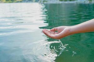 la main touche l'eau dans l'étang avec le soleil photo