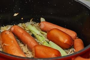 Saucisse fumée et chou dans une casserole avec bouquet de légumes verts pour faire de la choucroute alsacienne photo