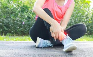 belle femme athlète a des douleurs à la cheville en faisant du jogging dans le parc. exercice sain photo
