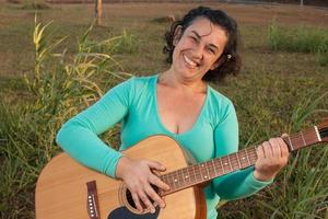 heureux femmes matures jouant et chantant sa guitare acoustique dans le parc photo