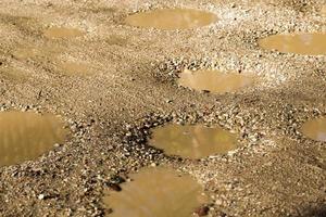 un grand nombre de nids de poule et de fosses sur la route sablonneuse photo