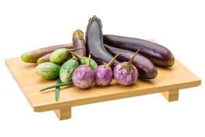 Assortiment d'aubergines asiatiques sur plaque de bois et fond blanc photo