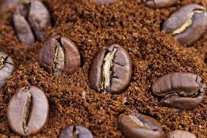 les grains de café torréfiés sont placés sur du café moulu photo