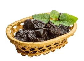 prunes séchées dans un panier sur fond blanc photo