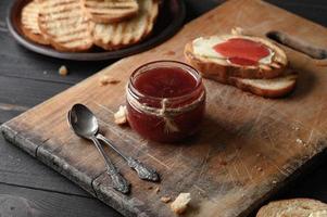 pain grillé avec de la confiture de fraises maison et sur une table rustique avec du beurre pour le petit déjeuner ou le brunch. photo