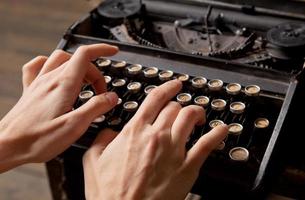 empreintes de mains humaines sur machine à écrire rétro.