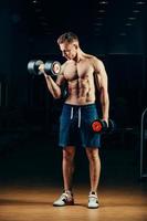 Bodybuilder musculaire athlète retour avec haltère dans la salle de gym photo