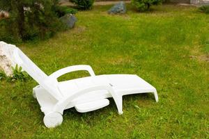 Chaise longue en plastique blanc sur une pelouse verte photo