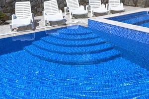 piscine avec échelle d'eau bleue pour descente et remontée dans l'eau. les transats sont vides au bord de la piscine. photo