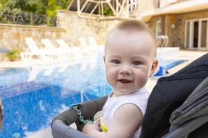 beau petit garçon est assis dans un landau au bord de la piscine. mise au point sélective photo