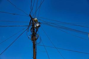 poteau de rue avec de nombreux fils électriques et câbles à fibres optiques, câble à fibres optiques contre le ciel bleu. photo