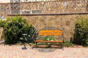 banc en bois vide avec un cendrier lors d'une journée d'été ensoleillée avec un cactus sur le fond d'un mur de pierre. style méditerranéen. photo