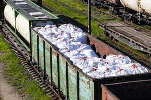 transport d'engrais dans d'énormes sacs et wagons par chemin de fer. wagons à engrais, train de marchandises. photo