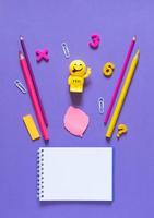 concept de retour à l'école. fournitures scolaires et de bureau sur la table de bureau. fond violet. mise à plat photo