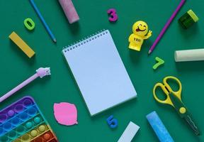 concept de retour à l'école. fournitures scolaires et de bureau sur la table de bureau. joyeux petit homme avec l'inscription oui et jouet antistress. mise à plat photo