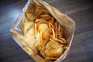Chips de pommes de terre dans un sac à collation ouvert en gros plan sur le sol de la table photo