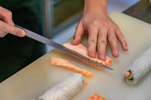 couper le saumon avec un couteau, chef japonais faisant du sashimi en cuisine, des sushis sont faits