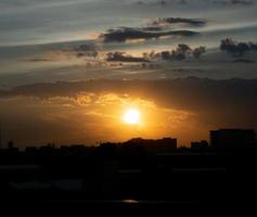 donne une sensation de chaleur, coucher de soleil derrière le bâtiment de la ville, silhouette des grands bâtiments de la ville, silhouette du bâtiment à nouveau beau fond de ciel et concept de liberté. photo