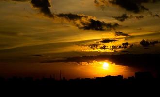 donne une sensation de chaleur, coucher de soleil derrière le bâtiment de la ville, silhouette des grands bâtiments de la ville, silhouette du bâtiment à nouveau beau fond de ciel et concept de liberté. photo