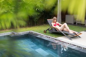 femme se détendre sur une chaise longue près de la piscine. photo