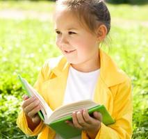 petite fille lit un livre à l'extérieur photo