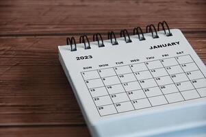 janvier 2023 calendrier de bureau blanc sur fond de table en bois. notion de calendrier photo