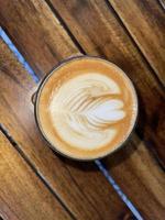 belle tasse de cappuccino avec art latte dans le fond de l'espace en bois photo