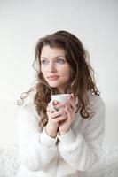 femme avec une tasse de café sur le lit