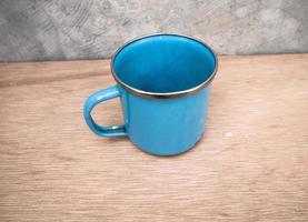 photo en gros plan d'une tasse de fer bleue isolée sur le fond sur une planche de bois