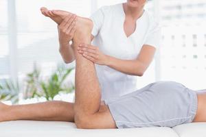 physiothérapeute faisant un massage des jambes à son patient photo