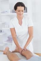 physiothérapeute faisant massage des mollets à son patient