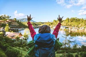 fille avec support de sac à dos avec impatience sur la belle vue sur le lac. voyageur touristique regardant la lumière du soleil sur les montagnes en voyage à mae hong son, en thaïlande. photo