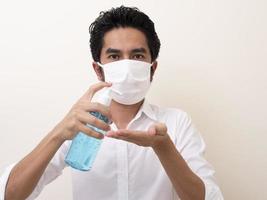 un homme portant un masque utilise actuellement du gel d'alcool pour se laver les mains photo