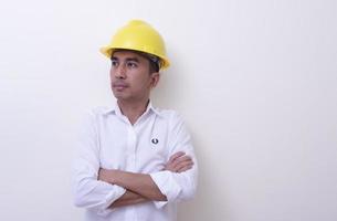 ingénieur avec les mains croisées portant un casque jaune sur fond blanc photo