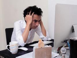 un homme asiatique sérieux travaille avec un ordinateur portable dans la chambre de son appartement dans le concept de travail à domicile et de travail à domicile photo