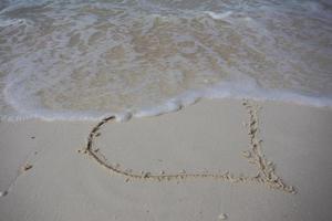 coeurs dessinés sur le sable d'une plage photo